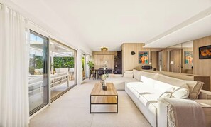 A modern living room with a sofa, a coffee table, and a dining area in the background. - ELEGANT 2-BEDROOM CANNES HOME 50M FROM THE CROISETTE WITH 25M² TERRACE (Cannes)