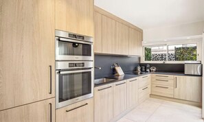 A modern kitchen with stainless steel appliances, light wood cabinetry, and a black countertop. - ELEGANT 2-BEDROOM CANNES HOME 50M FROM THE CROISETTE WITH 25M² TERRACE (Cannes)