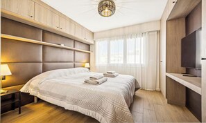 A modern bedroom with a bed, bedside lamps, a TV, and a large window with curtains. - ELEGANT 2-BEDROOM CANNES HOME 50M FROM THE CROISETTE WITH 25M² TERRACE (Cannes)