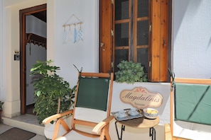 A wooden chair with a green cushion, a small table with a tray holding two cups and a bowl, and a sign that reads 'Magdalinis house.' - Magdalini's Holiday Home in Skopelos (Skopelos)