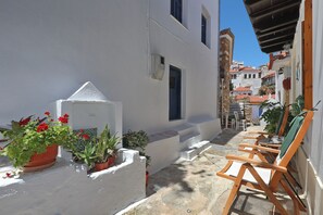 A narrow street with white buildings, a row of wooden chairs, and potted plants. - Magdalini's Holiday Home in Skopelos (Skopelos)