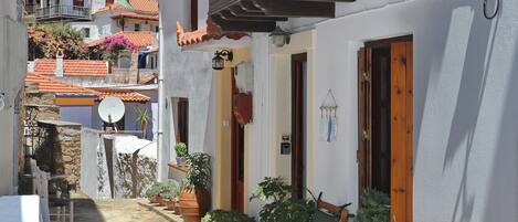 A courtyard with a seating area, potted plants, and a view of neighboring buildings.
