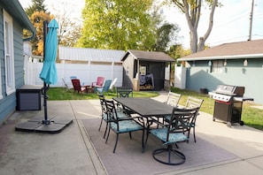 Eine Terrasse im Freien mit Tisch und Stühlen, einem Grill und einem überdachten Bereich mit Sitzgelegenheiten.