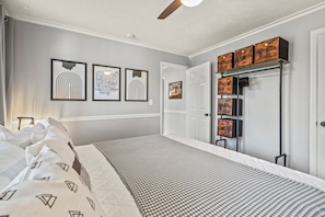 Ein Schlafzimmer mit einem Bett, einem Deckenventilator und gerahmten Kunstwerken an der Wand.