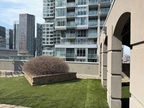 Un bâtiment moderne doté de nombreux balcons, d’une pelouse bien entretenue et offrant une vue sur les immeubles environnants.