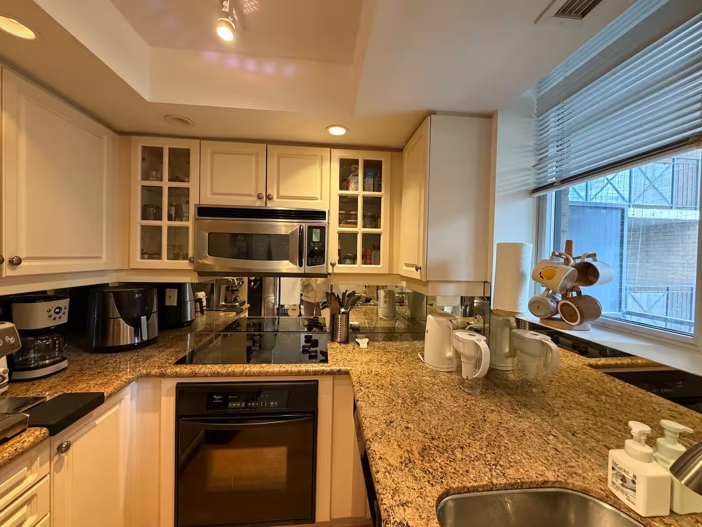 A modern kitchen with built-in appliances, a granite countertop, and a window with a view.