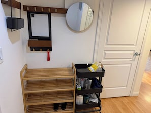 Ein Zimmer mit einem hölzernen Bett, einem schwarzen Rollwagen mit Reinigungsmitteln, einem Spiegel und einer weißen Tür.