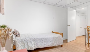 Ein Schlafzimmer mit einem Einzelbett, einer Holztür und einem kleinen Tisch mit Stühlen.