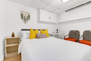 Ein Hotelzimmer mit Bett, Schreibtisch, zwei Stühlen, einem Kleiderschrank und einer Wanddekoration.