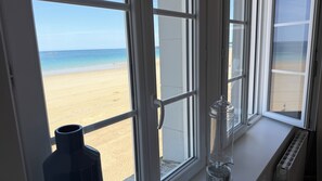 Een uitzicht op een zandstrand en de oceaan vanuit een raam.