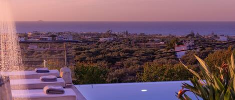 An infinity pool with a view of the sea and a cityscape.