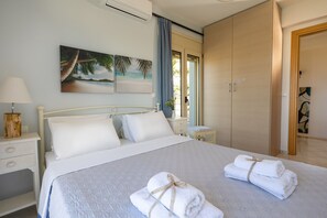 A bedroom with a bed, a nightstand, a dresser, and a window with curtains. - Villa Konstantinos in Heraklion (Hersonissos)