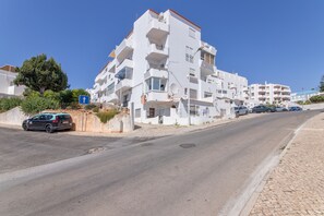 Ein mehrstöckiges Wohngebäude mit Balkonen, einer gepflasterten Straße und geparkten Autos.