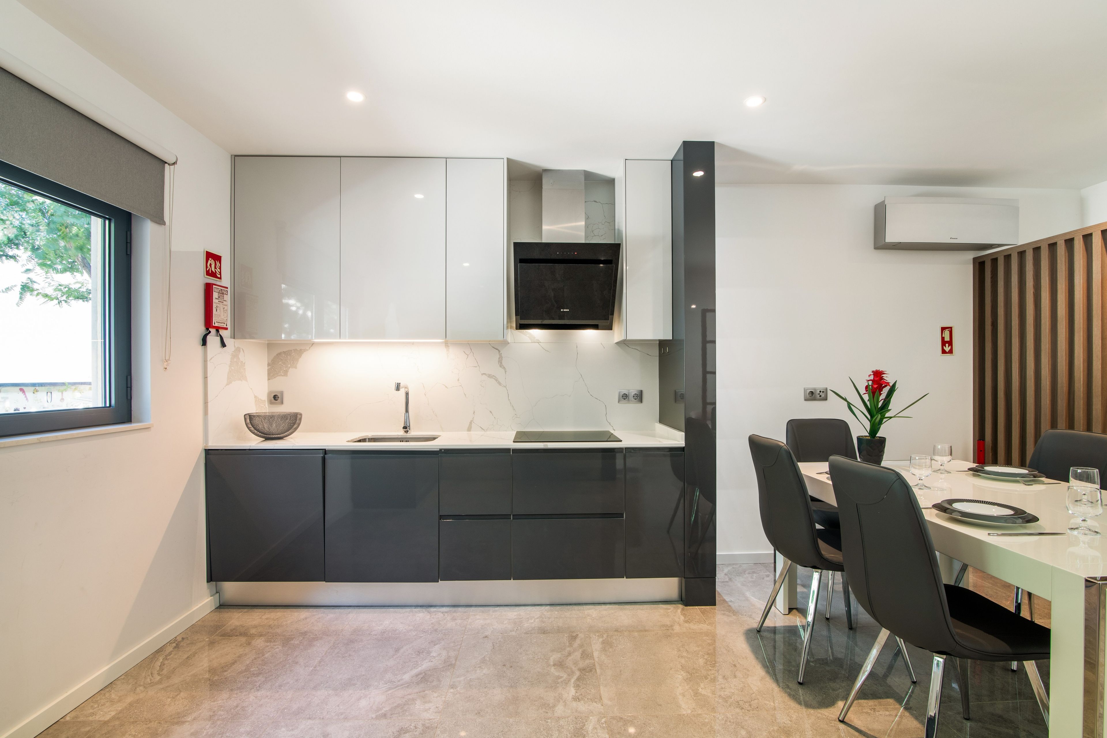 Une cuisine moderne dotée d’une cuisinière intégrée, un coin repas avec une table et des chaises, et une fenêtre donnant sur un paysage verdoyant.