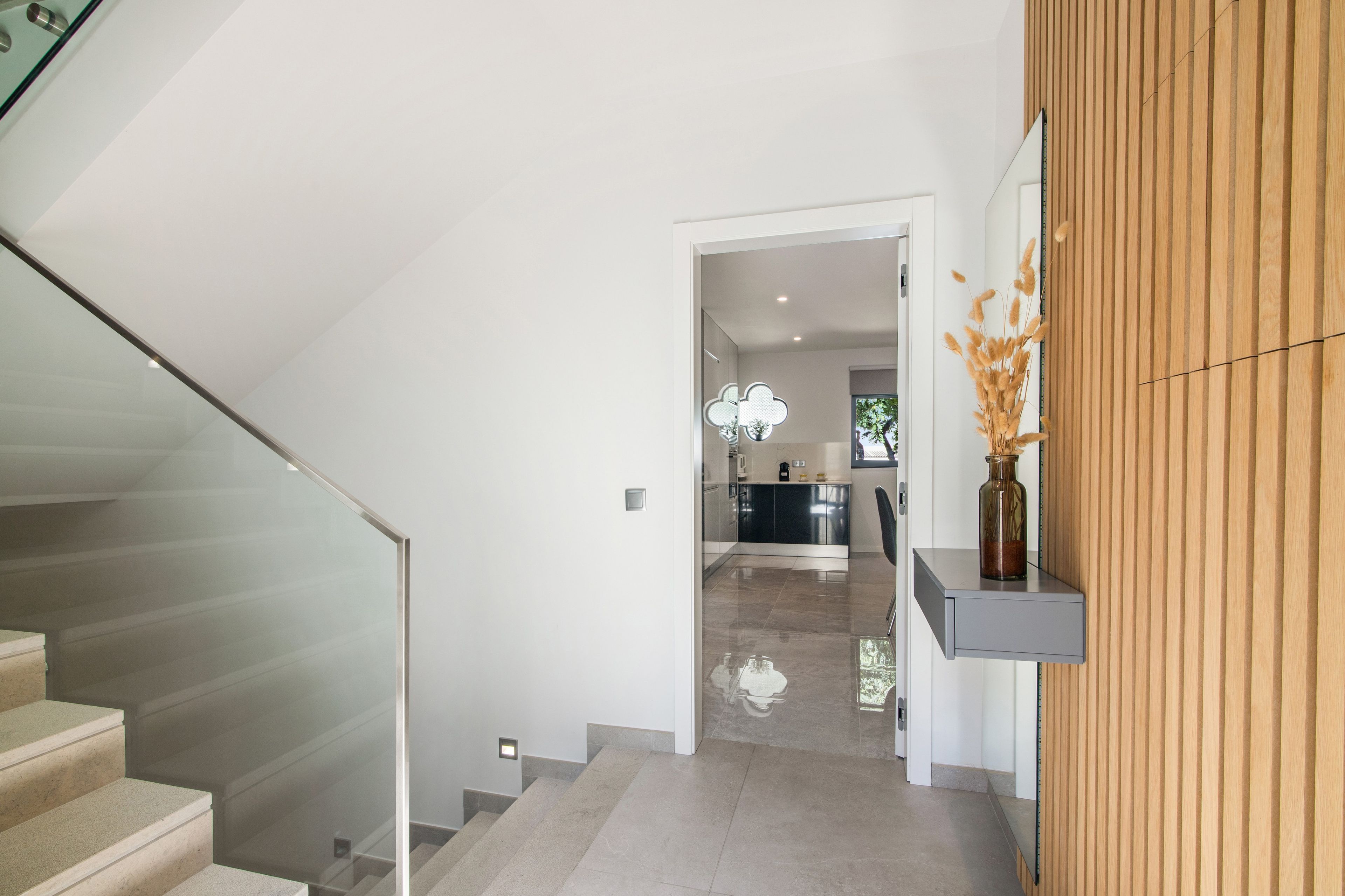 Un intérieur moderne avec un escalier, un coin cuisine et un mur d’accent en bois.