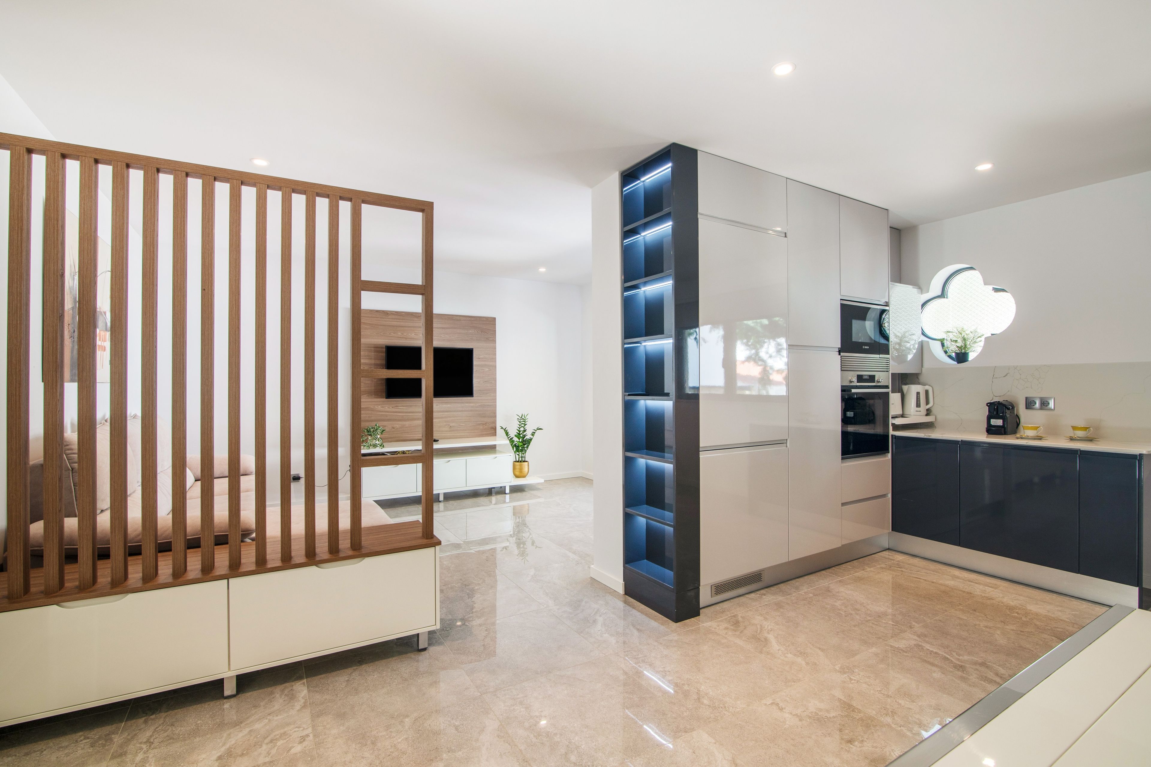 A modern kitchen with a built-in oven, a coffee machine, and a decorative light fixture.