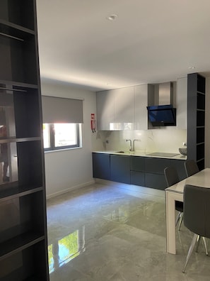 A modern kitchen with a built-in oven, a sink, and a dining area with a table and chairs. - Holiday Home 'Old Town Charm' with Private Terrace, Wi-Fi and Air Conditioning (Albufeira)