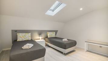 Une chambre moderne avec deux lits, une lucarne et une table de chevet avec une lampe.