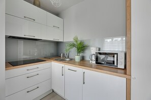 Una cocina moderna con armarios blancos, encimera de madera, cafetera Bosch y microondas Bosch.