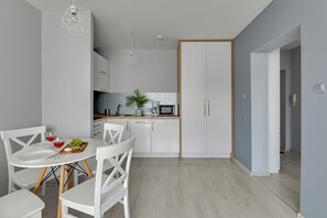 Una cocina moderna con armarios blancos, una mesa de comedor con sillas y una pequeña isla con microondas.