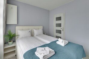 Habitación de hotel con cama, planta en maceta, puerta y toalla sobre la cama.