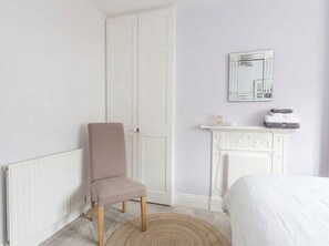 A bedroom with a white radiator, a chair, a bed, a white fireplace, and a mirror on the wall. - Court Hill Haven,
A wonderful base for your Swanage stay. (Swanage)