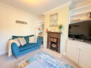 A living room with a blue sofa, a fireplace, a television, and a bookshelf. - Court Hill Haven,
A wonderful base for your Swanage stay. (Swanage)