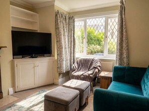 A living room with a television, a sofa, an ottoman, a chair, and a window with curtains. - Court Hill Haven,
A wonderful base for your Swanage stay. (Swanage)