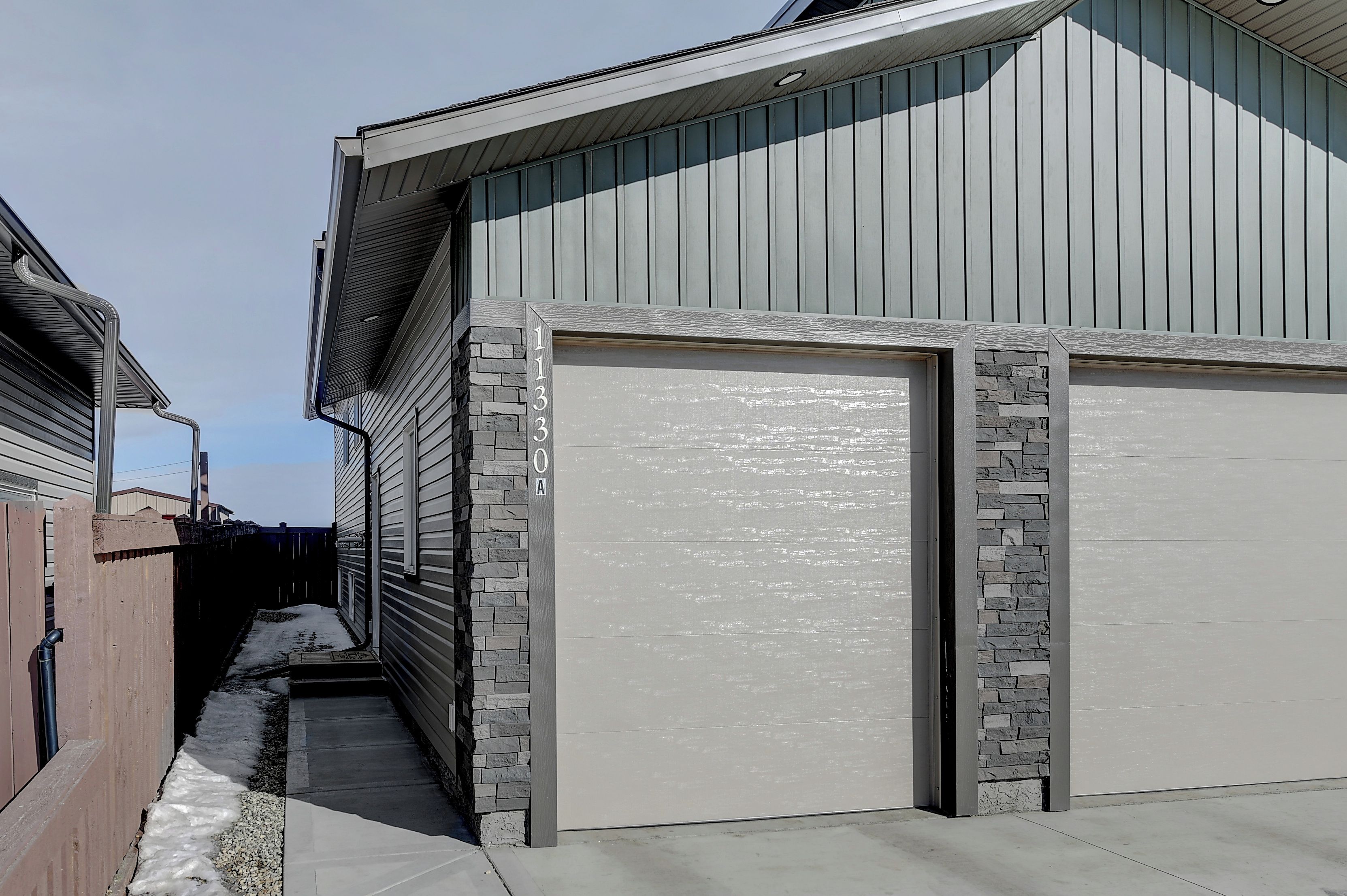 A residential garage with a stone accent wall and a clear driveway.