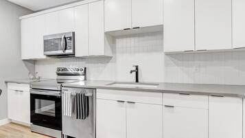 Una cucina moderna con mobili bianchi, elettrodomestici in acciaio inossidabile e una parete backsplash piastrellata.
