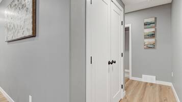 A hallway with a white door, a painting on the wall, and a light switch.