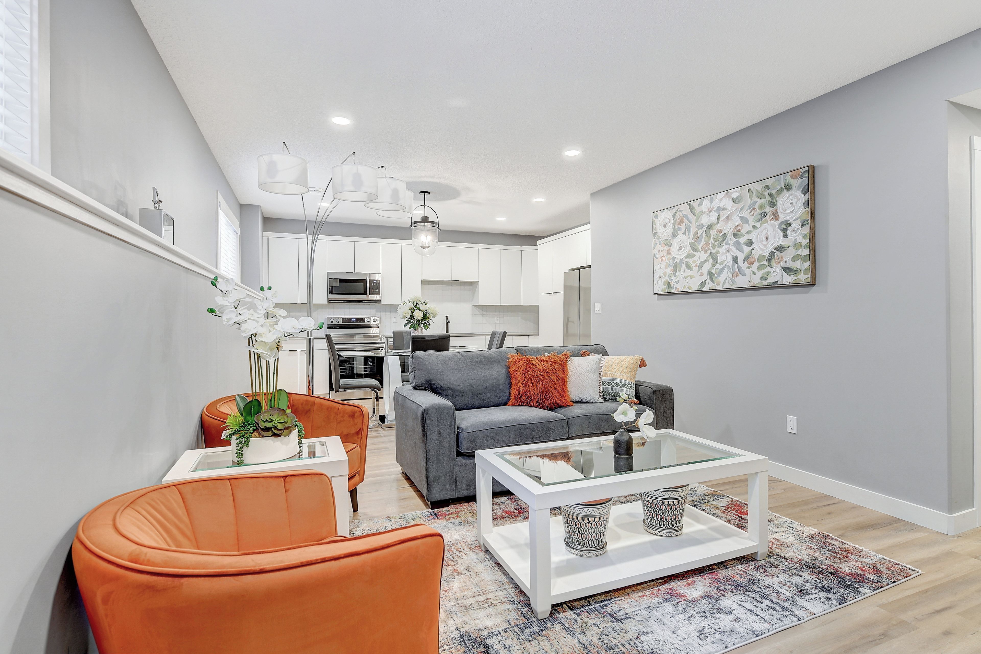 Un salon moderne avec un canapé gris, un fauteuil orange et une table basse.