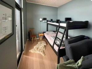 A room with bunk beds, a desk, a chair, and a framed picture on the wall.