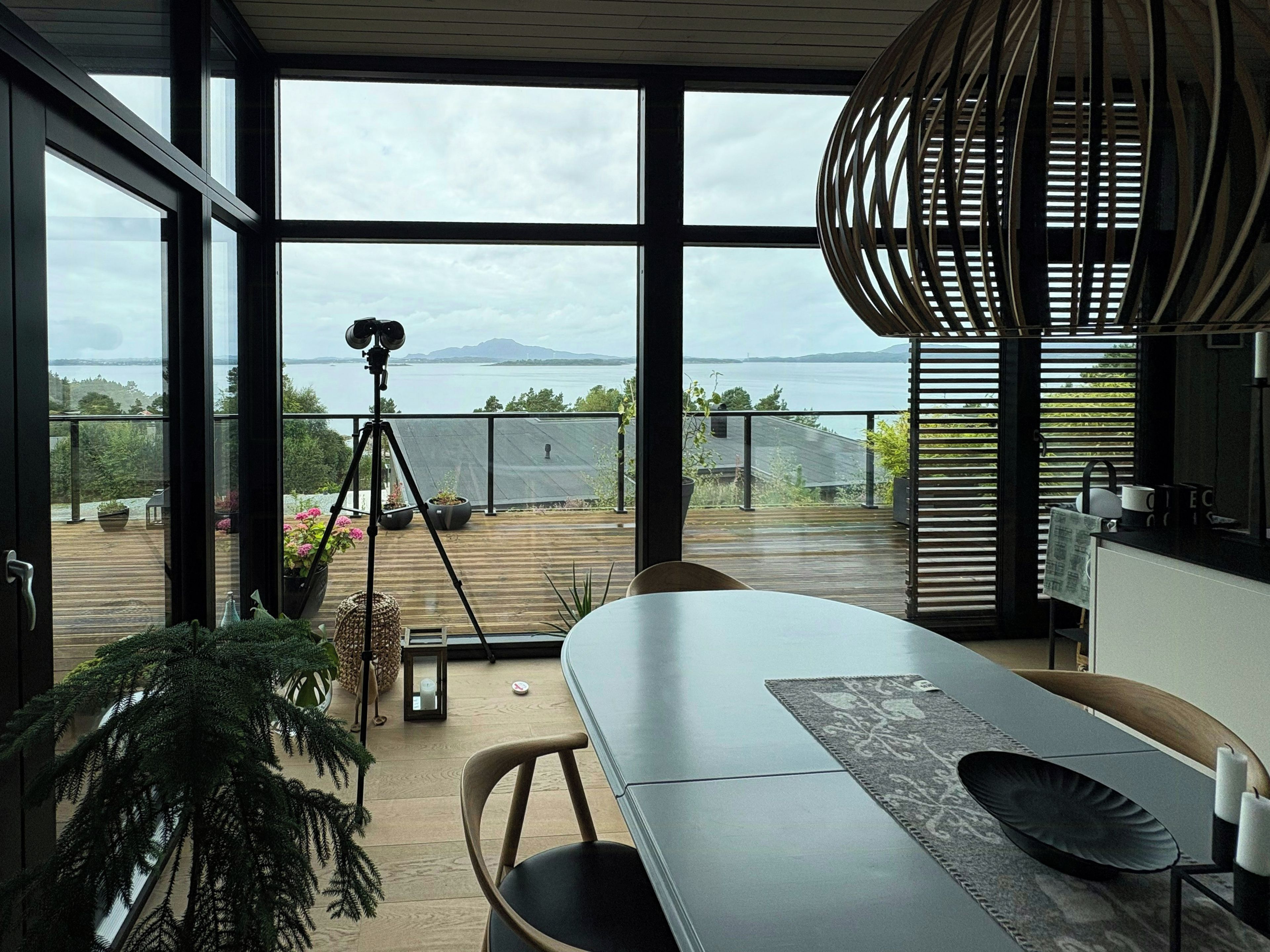 A modern interior with a large window overlooking a deck and water.