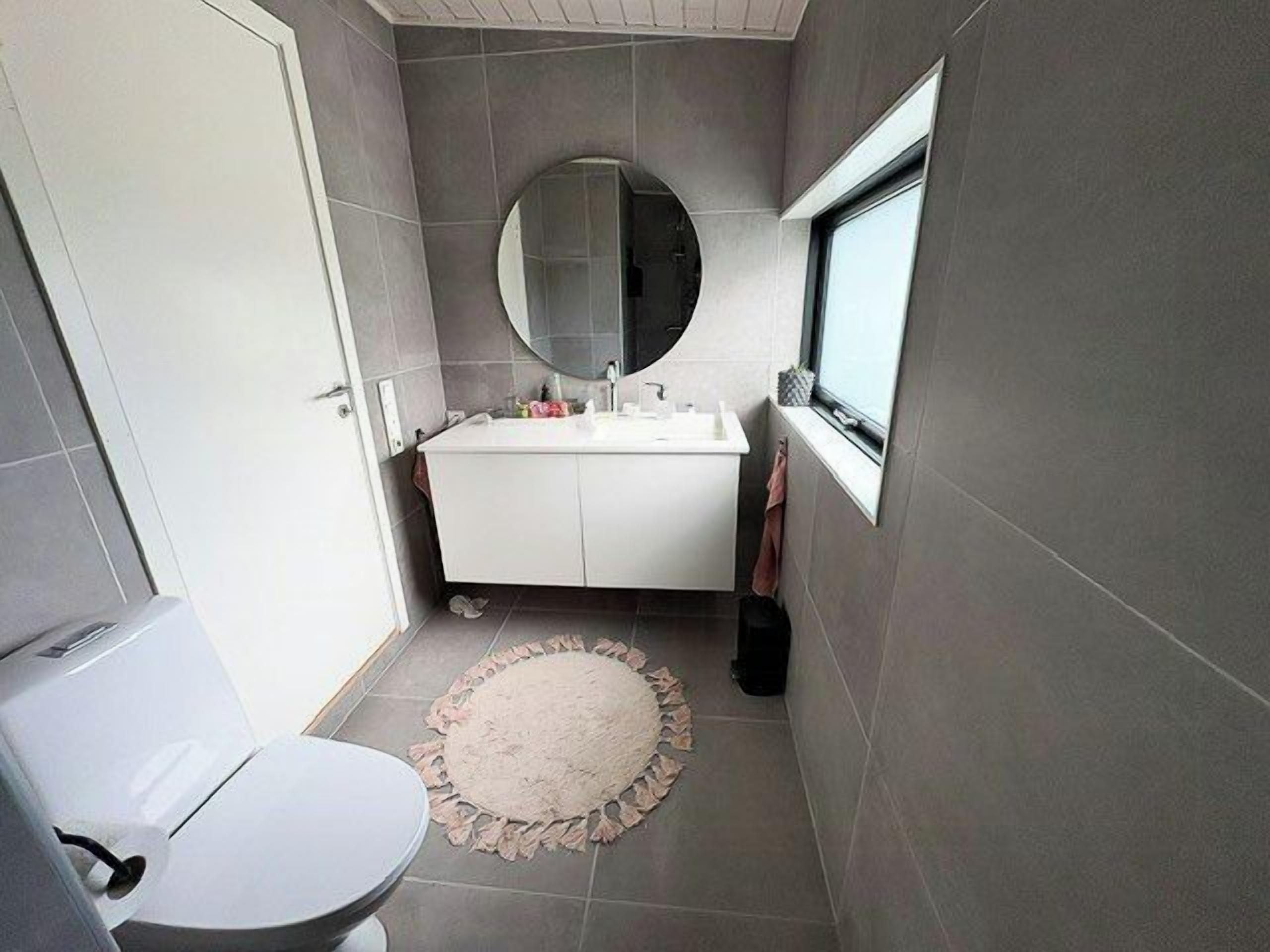 Un baño pequeño con inodoro, lavamanos y espejo.