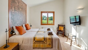 A bedroom with two beds, a television, a window with a view of greenery, and a brick wall. - Country House 'Son Bartolo' with Private Terrace, Wi-Fi and Air Conditioning (Inca)