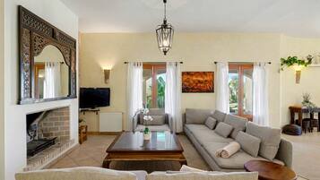 A living room with a fireplace, sofa, coffee table, and a television.