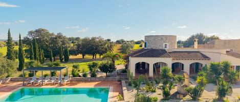 Eine Villa mit Swimmingpool, Sitzgelegenheiten im Freien und Blick auf die Landschaft.