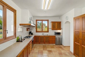 A kitchen with wooden cabinets, a stainless steel dishwasher, and a window with a view of greenery.