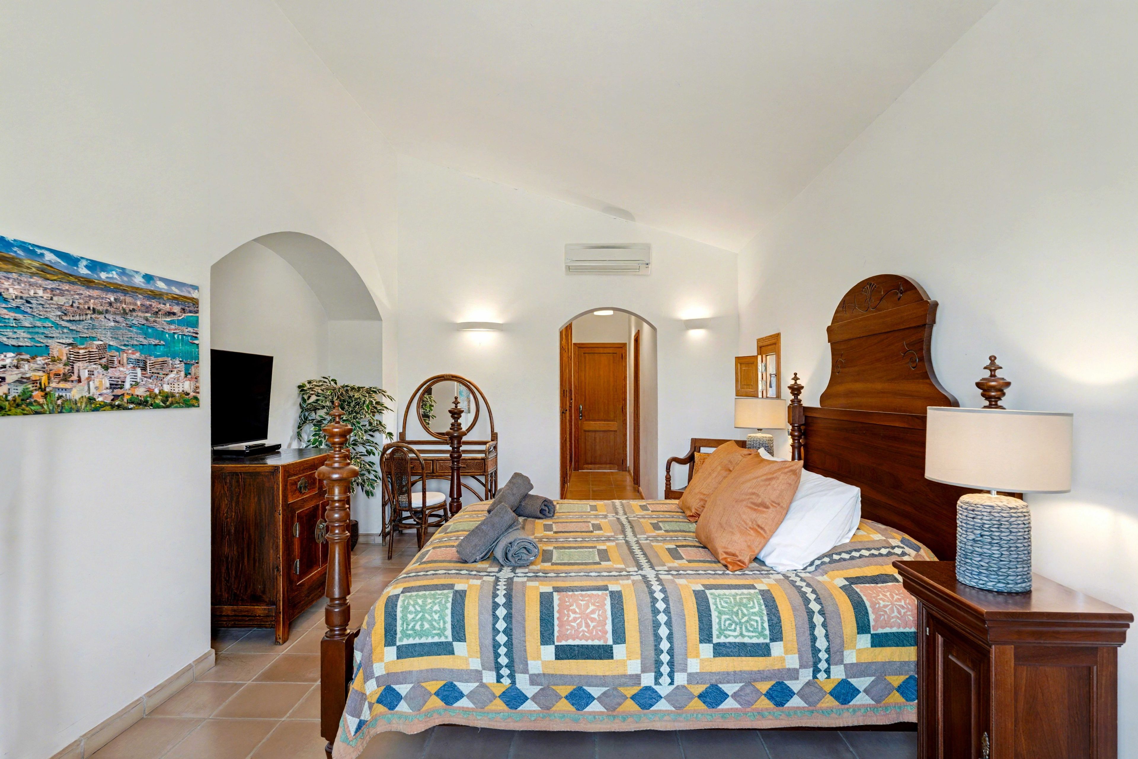 A bedroom with a bed, a dresser, a chair, a desk, and a television.