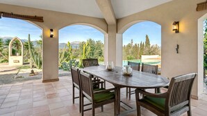 A covered patio with a table and chairs, a ceiling fan, and views of a mountainous landscape. - Country House 'Son Bartolo' with Private Terrace, Wi-Fi and Air Conditioning (Inca)