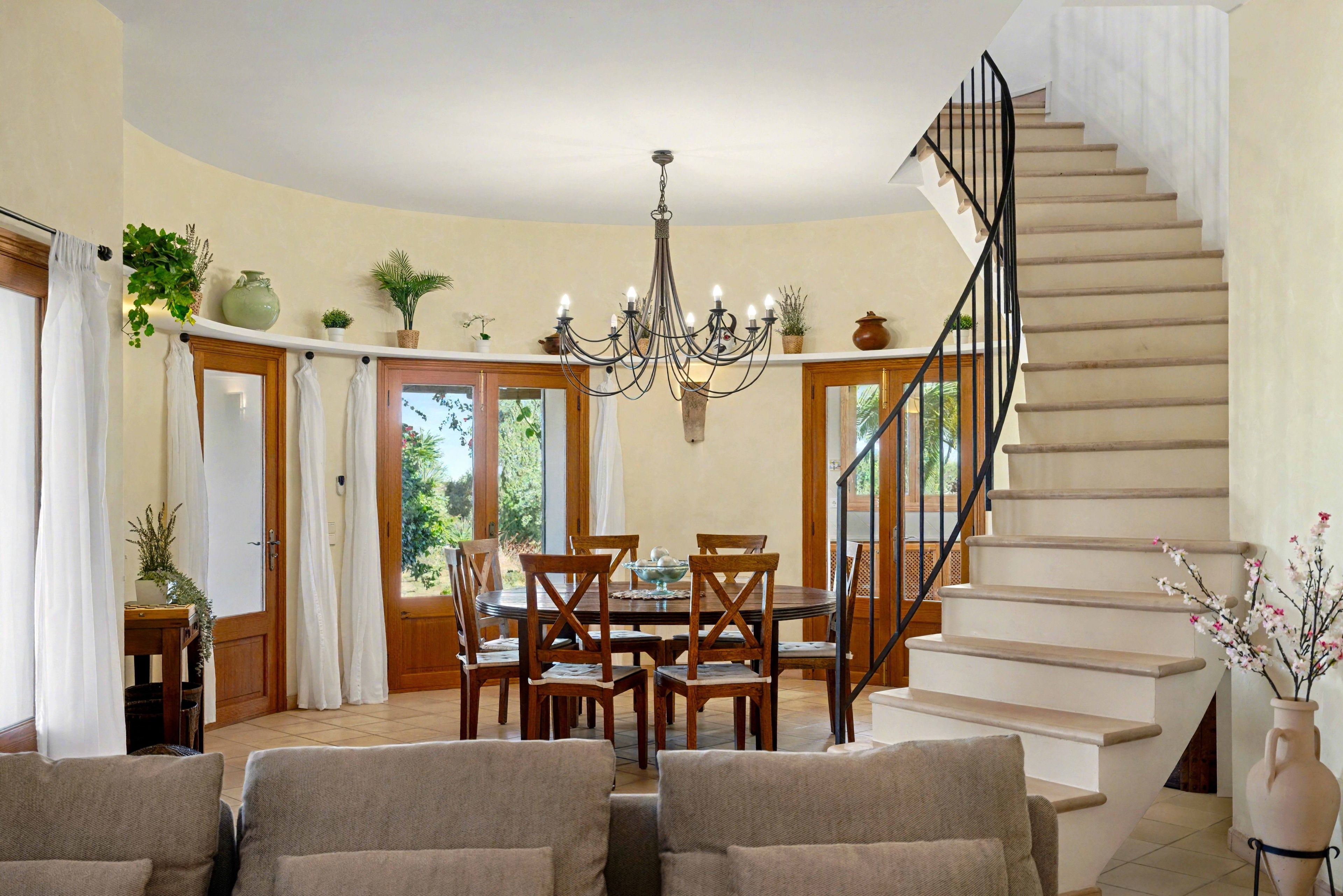 A dining area with a chandelier, wooden chairs, and a table.