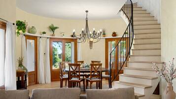 A dining area with a chandelier, wooden chairs, and a table.