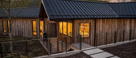 A modern building with a metal roof, wooden walls, and a covered outdoor area with steps leading to a door.