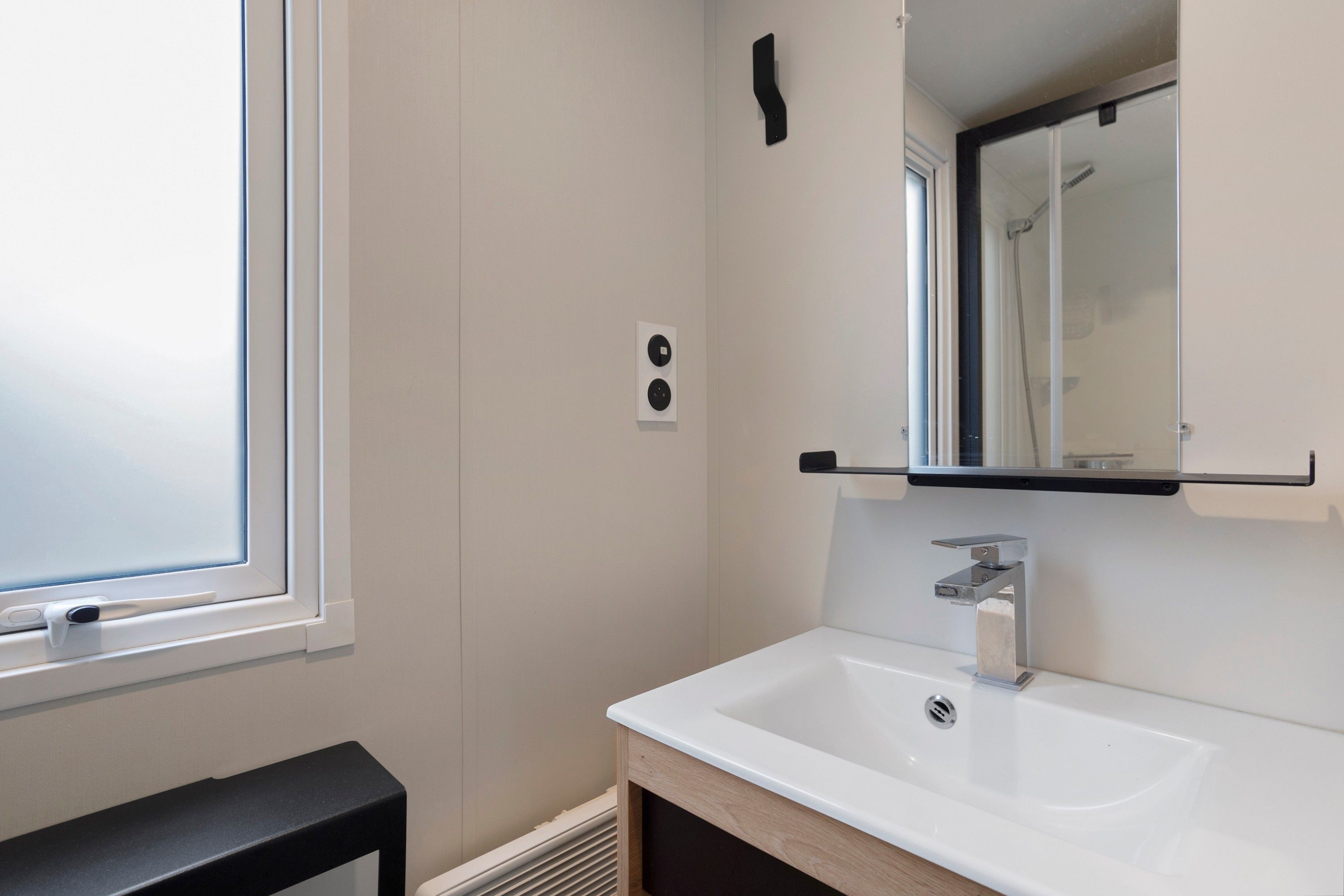 Un baño con un lavabo blanco, un espejo y una ventana.