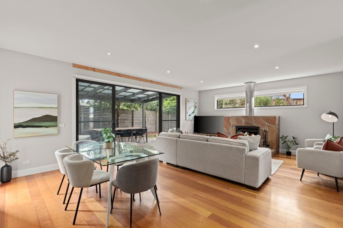 A spacious living room with a glass dining table, a large sofa, and a fireplace.