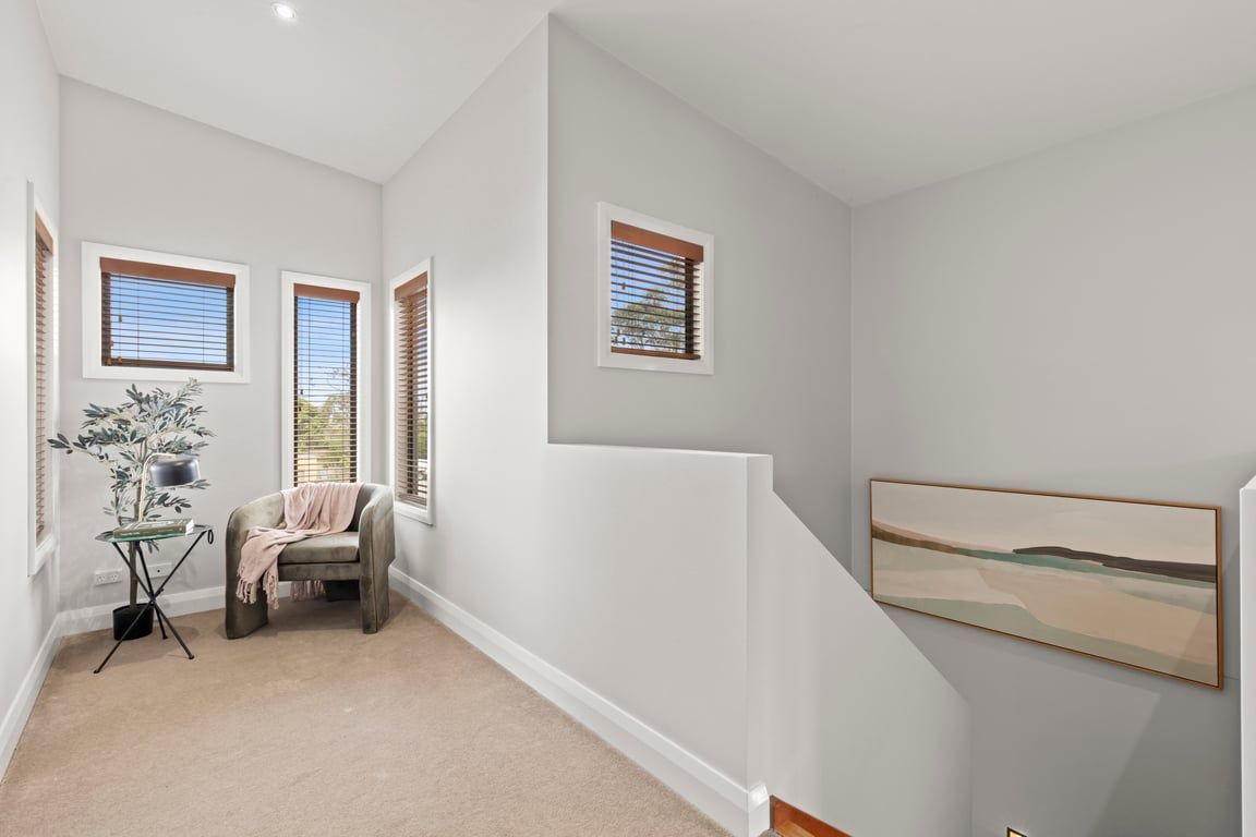 A hallway with a staircase, a potted plant, and a framed picture on the wall.