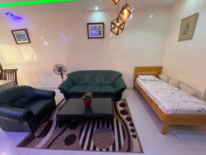 Ein Wohnzimmer mit einer Couch, einem Couchtisch, einem Ventilator und einem Bett.