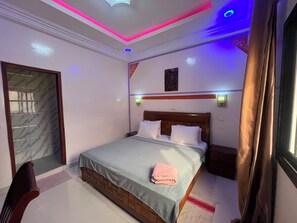 Ein Hotelzimmer mit einem Bett, Nachttischen, Vorhängen an einem Fenster und einer Tür zu einem Badezimmer.