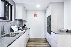A modern kitchen with a stainless steel sink, a built-in oven, and a microwave. - Villa Maria Luisa - Four Bedroom Villa, Sleeps 8 (Olhos de Água)